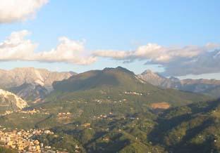 dalle alture di Santa Lucia: la Brugiana spicca col verde dei suoi boschi mentre dietro ci sono le Apuane: a sx il Sella e a dx l’Altissimo.